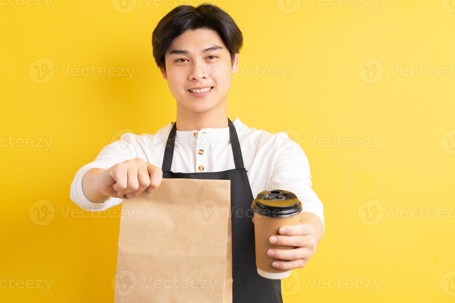 retrato, de, macho, camarero, tenencia, taza de papel, en, mano, sobre fondo amarillo foto