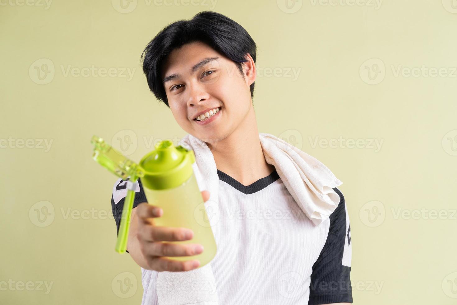 Hombre asiático sosteniendo agua en la mano sobre fondo verde foto