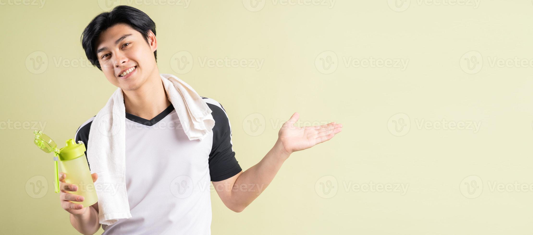 Hombre asiático sosteniendo agua en la mano sobre fondo verde foto