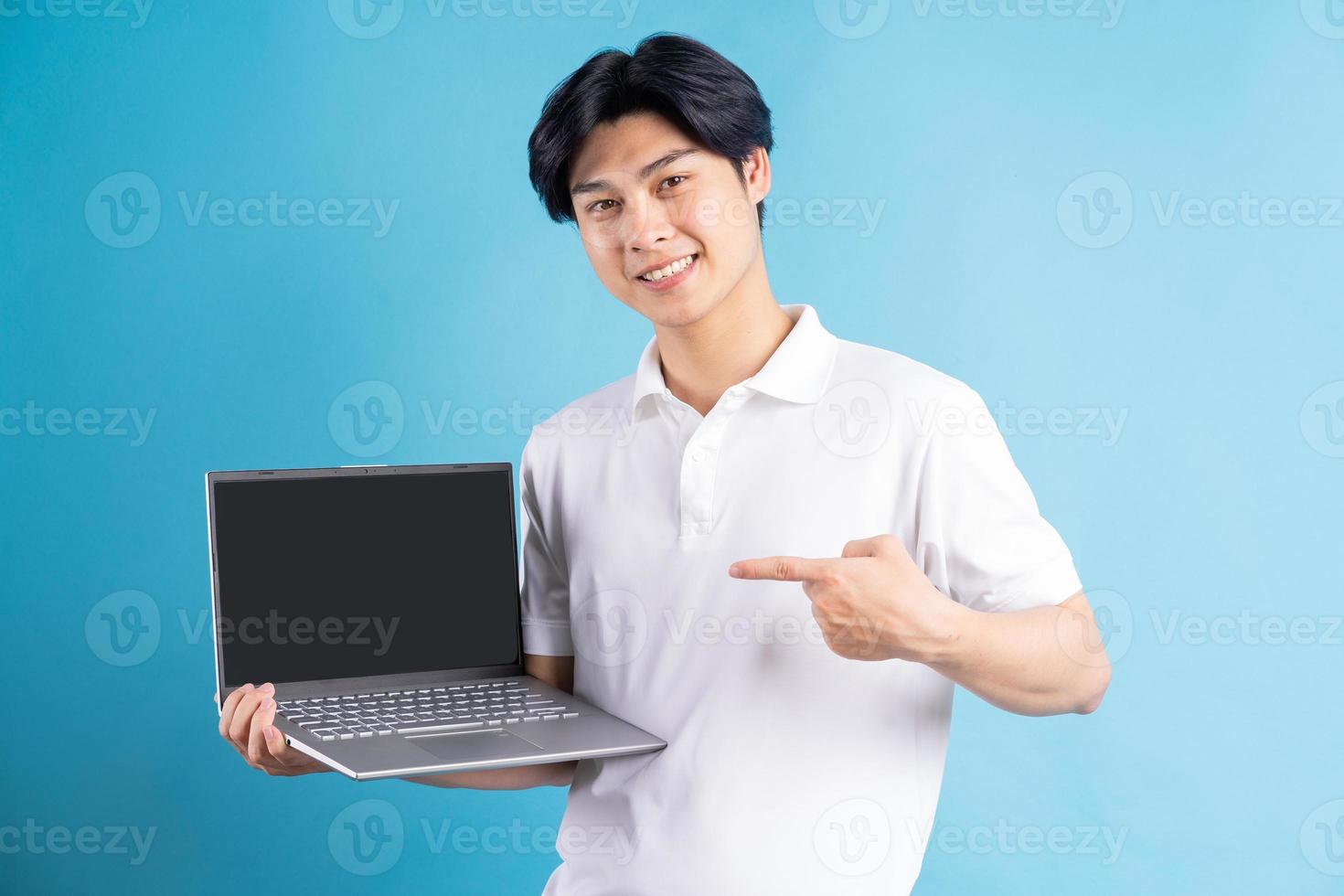 el hombre asiático apuntaba con el dedo a la computadora portátil con una pantalla en blanco foto