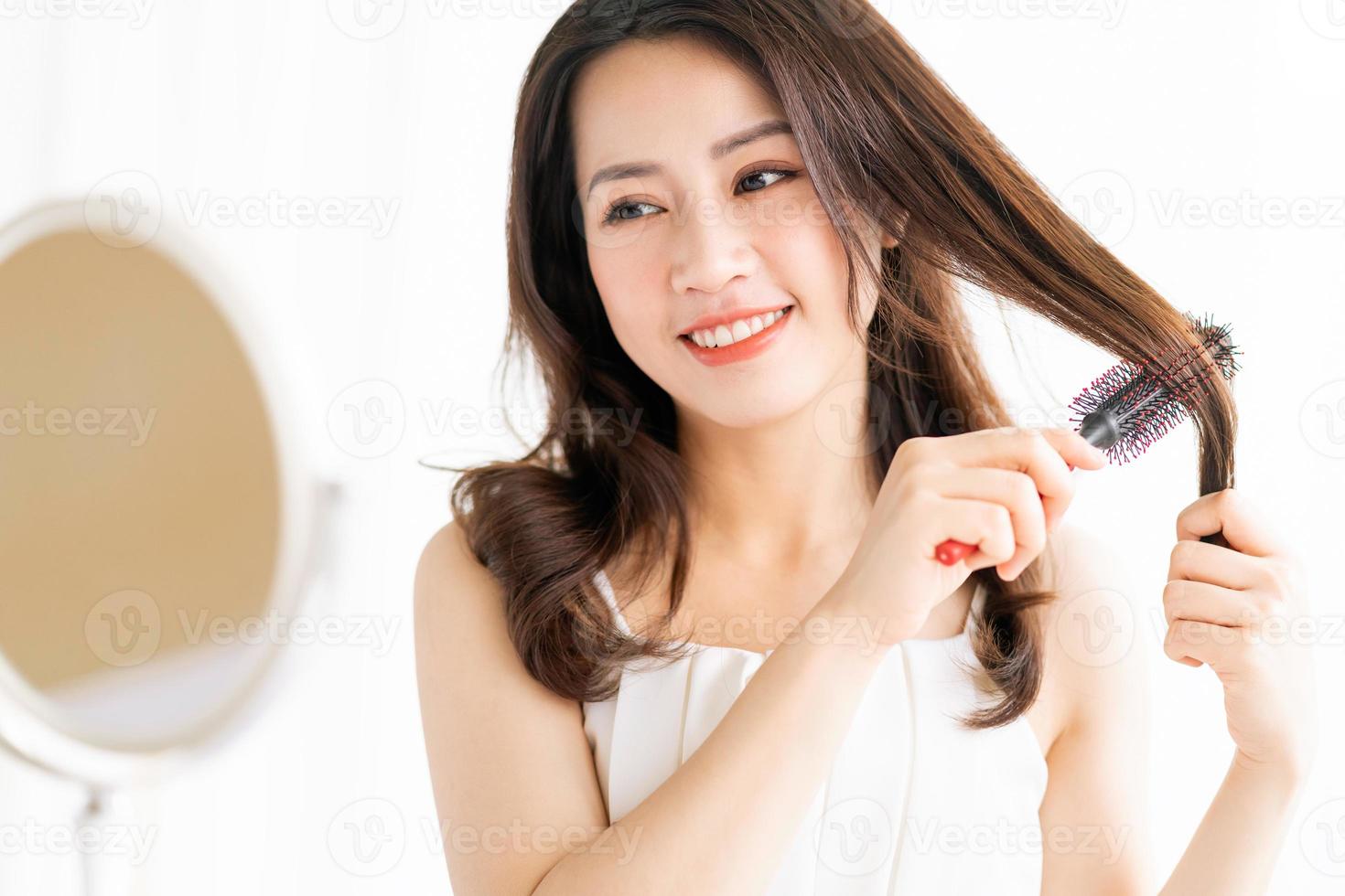 mujer sentada cepillándose el pelo con una expresión feliz foto
