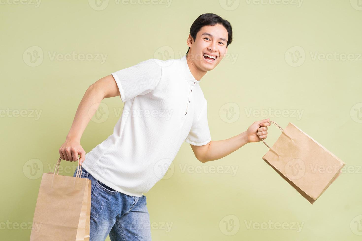 The handsome Asian man is holding paper bags in his hand photo