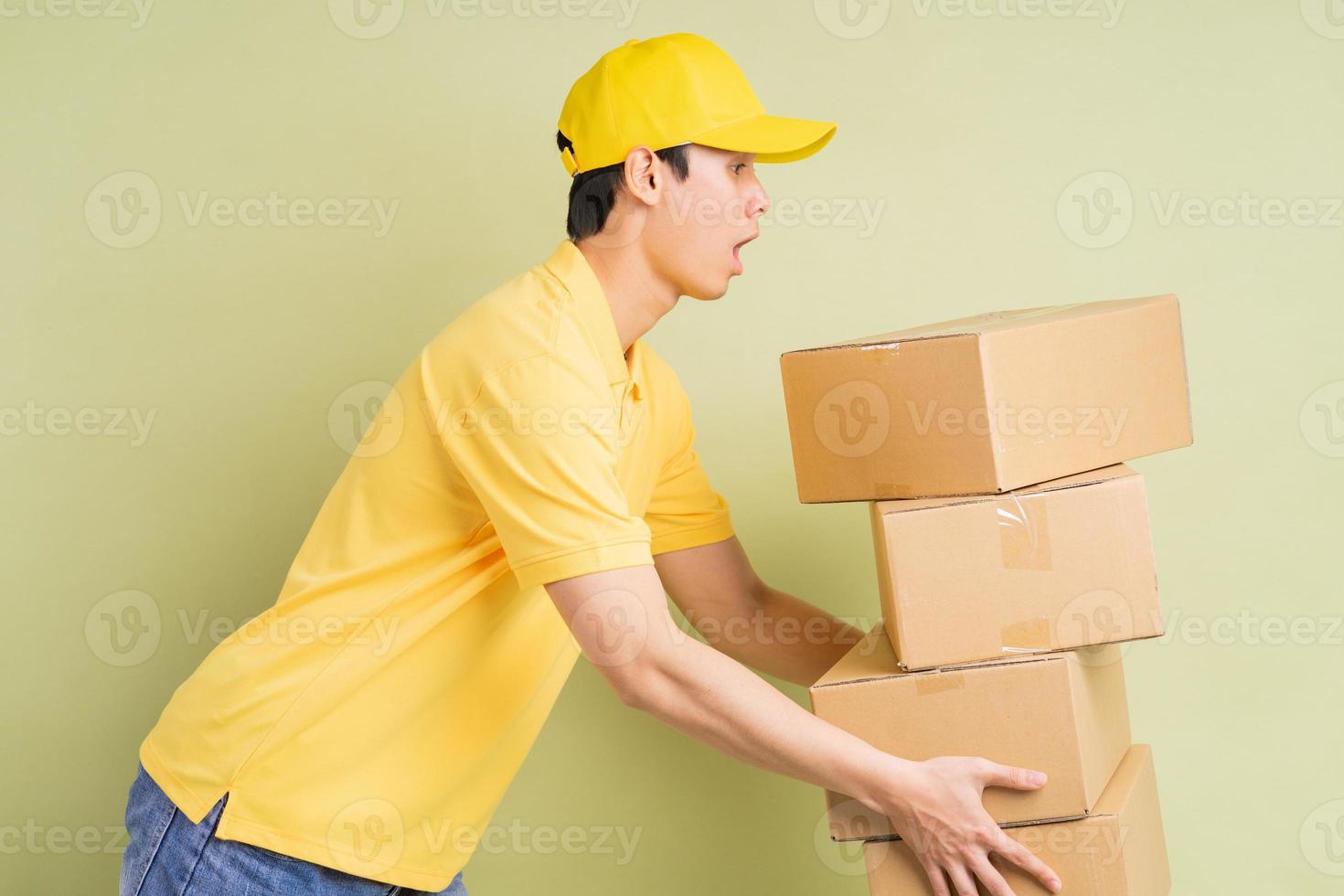 El repartidor asiático sostiene la caja con él y corre para entregar la mercancía. foto