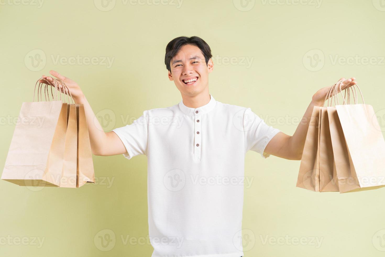 The handsome Asian man is holding paper bags in his hand photo