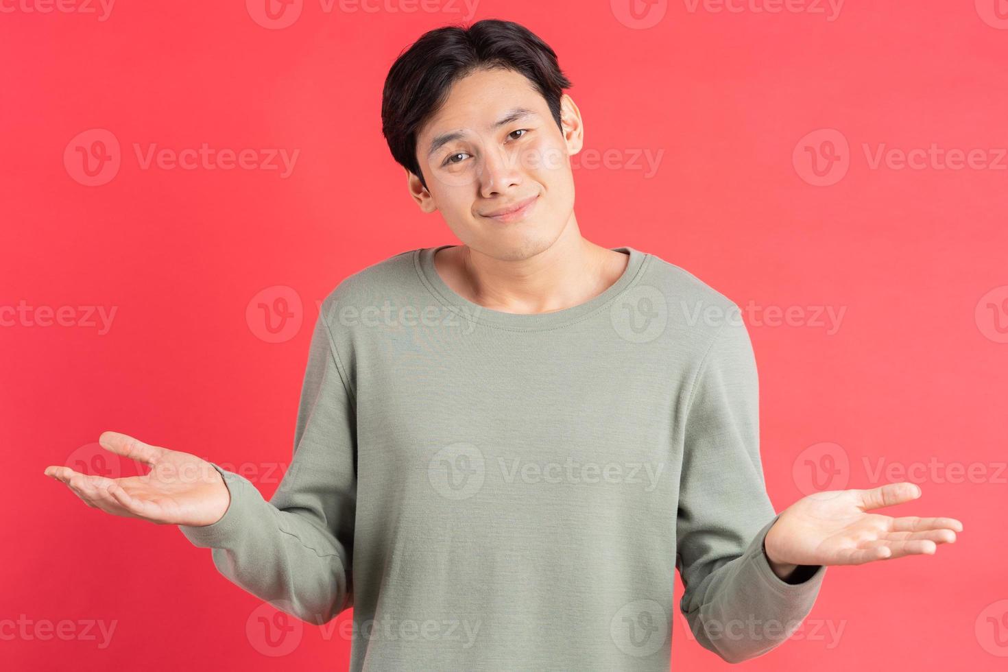 A photo of a handsome Asian man shrugging his shoulders in confusion