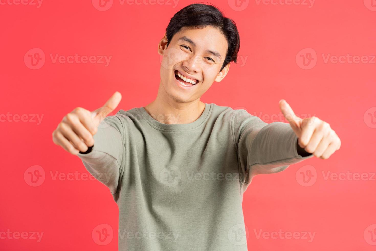 Una foto de un apuesto hombre asiático sosteniendo 2 pulgares con una cara alegre