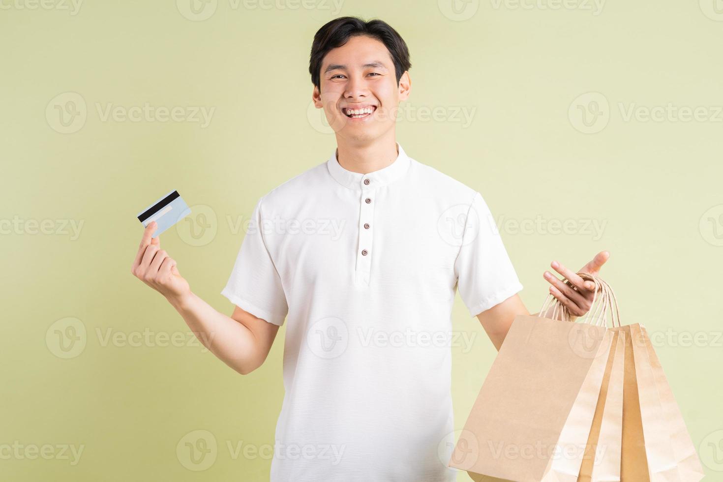 Apuesto hombre de negocios asiático sosteniendo una tarjeta de crédito y llevando bolsas de la compra. foto