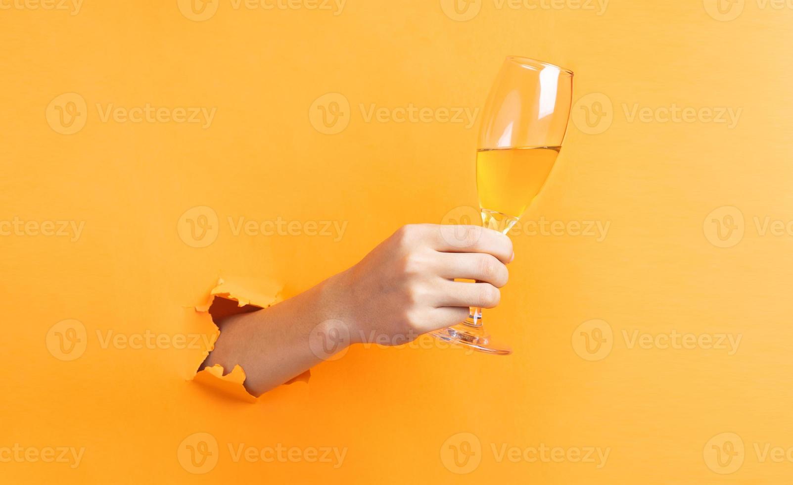 Hand holding wine glasses protruding from background photo