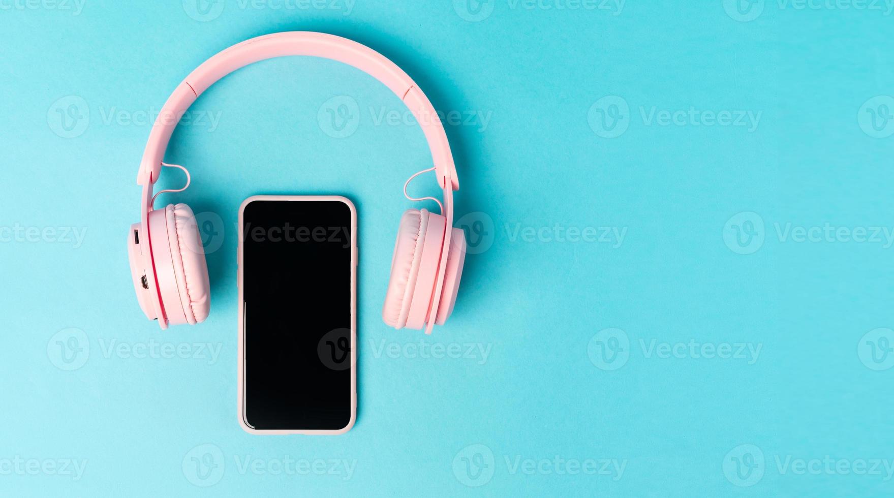 Pink phone and headphones on a blue background photo