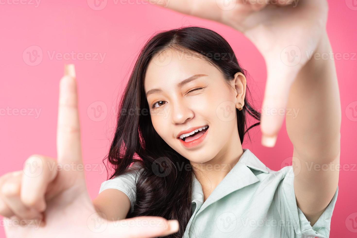 joven mujer asiática usando sus manos para formar un marco foto
