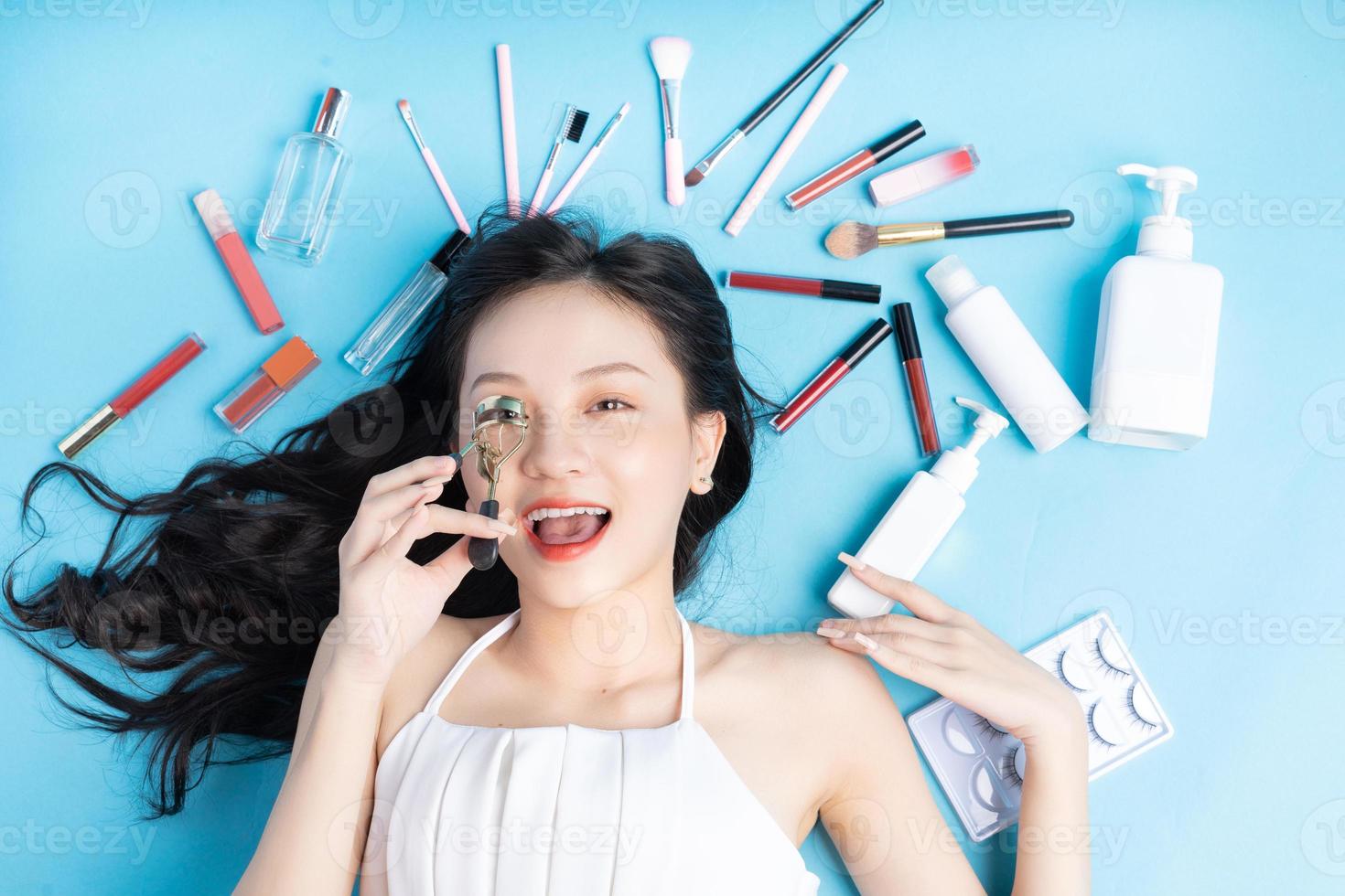 mujer asiática, acostado, en, fondo azul, con, maquillaje, alrededor foto