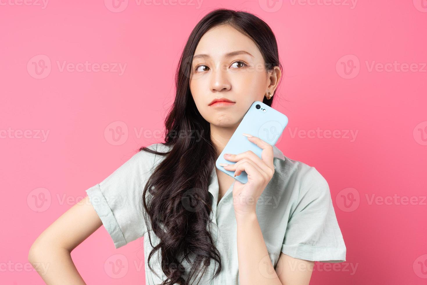 Joven mujer asiática sosteniendo el teléfono en la mano con mirada pensativa foto