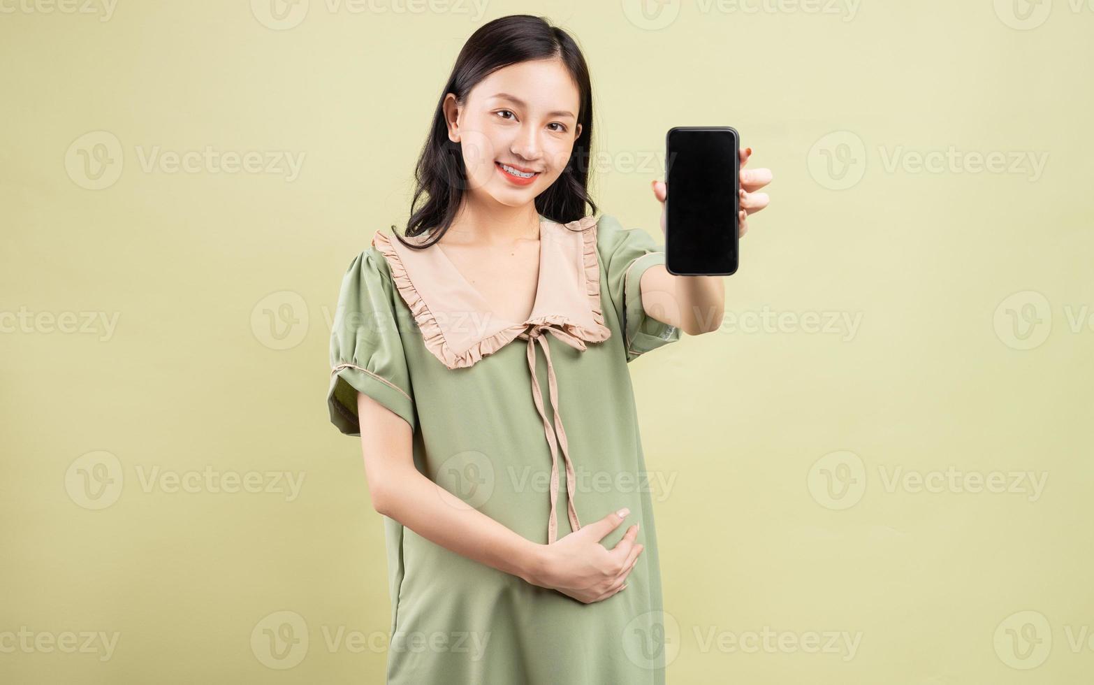 Pregnant Asian woman holding phone in hand photo