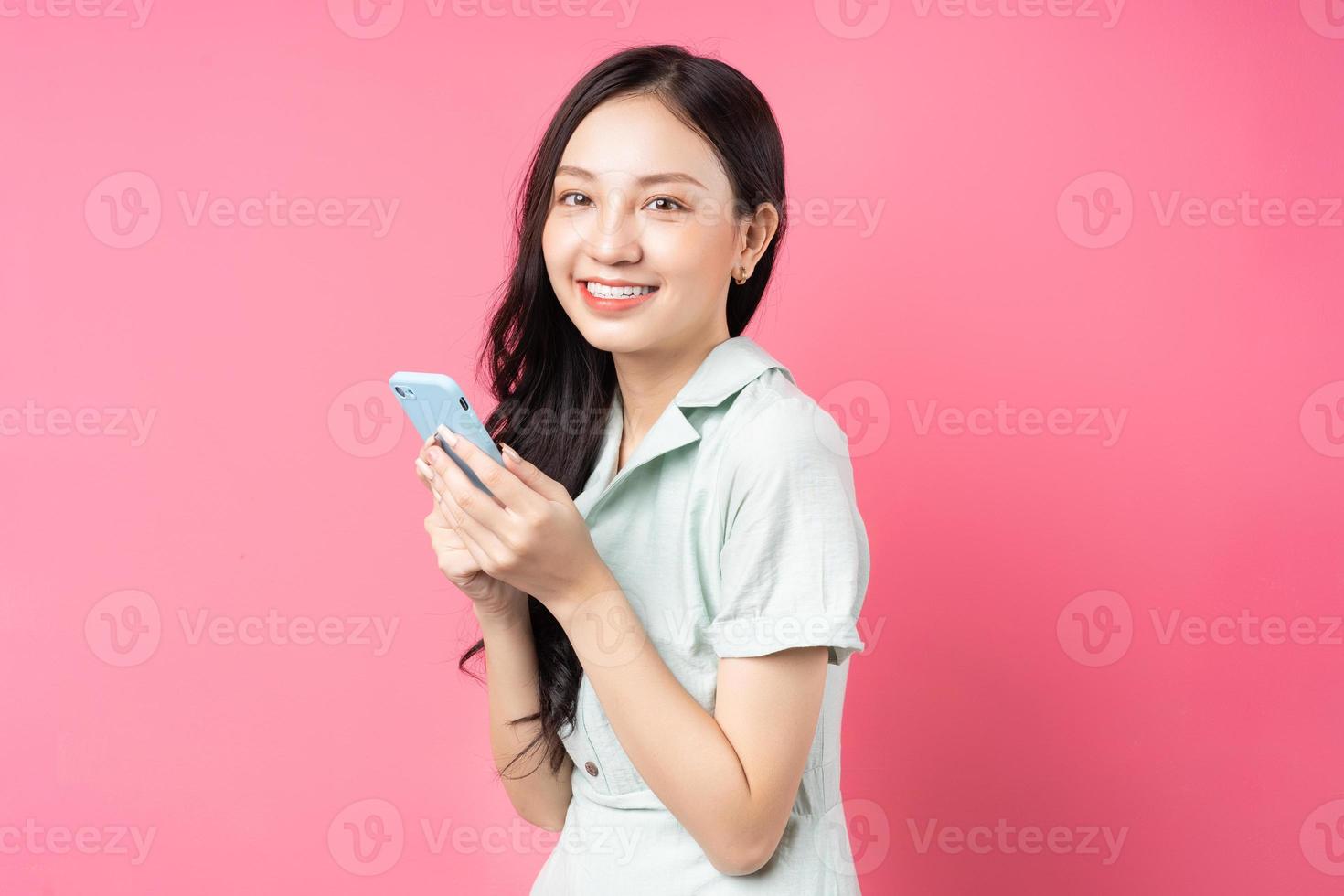 joven mujer asiática sosteniendo el teléfono para enviar un mensaje de texto foto