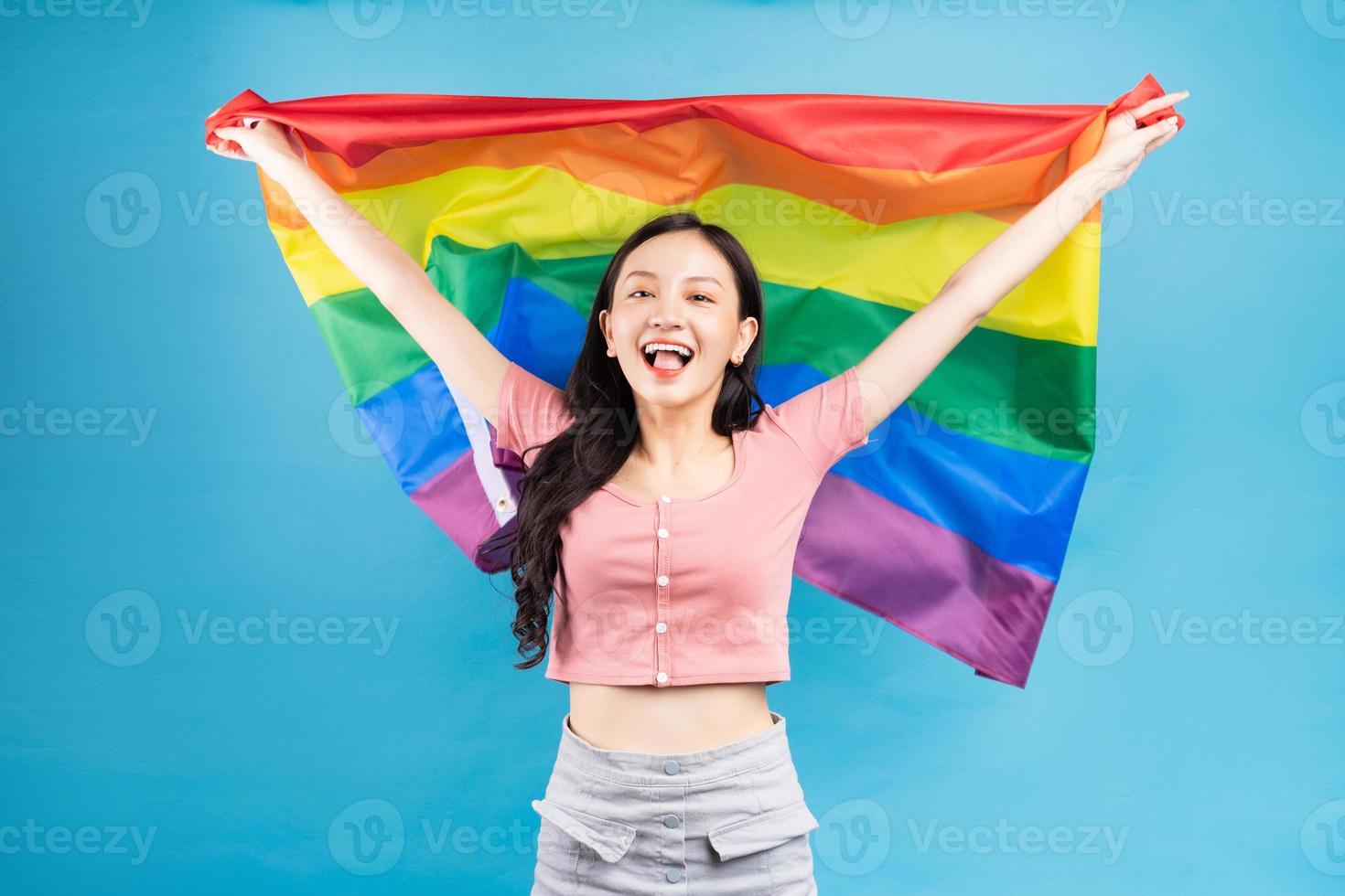 joven asiática sosteniendo la bandera del arco iris para apoyar a la comunidad lgbtq foto