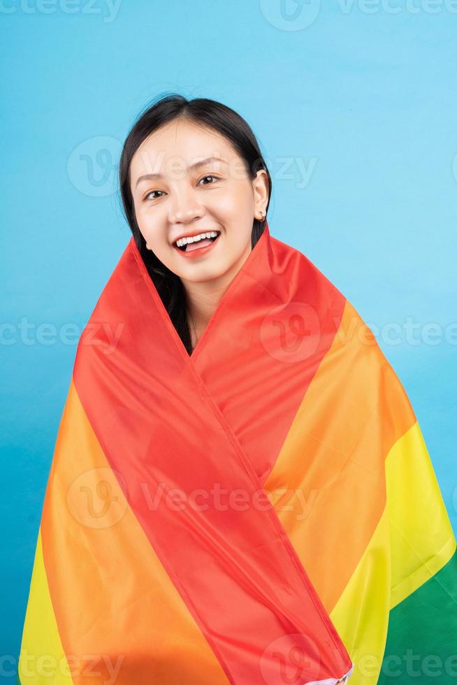 joven asiática sosteniendo la bandera del arco iris para apoyar a la comunidad lgbtq foto