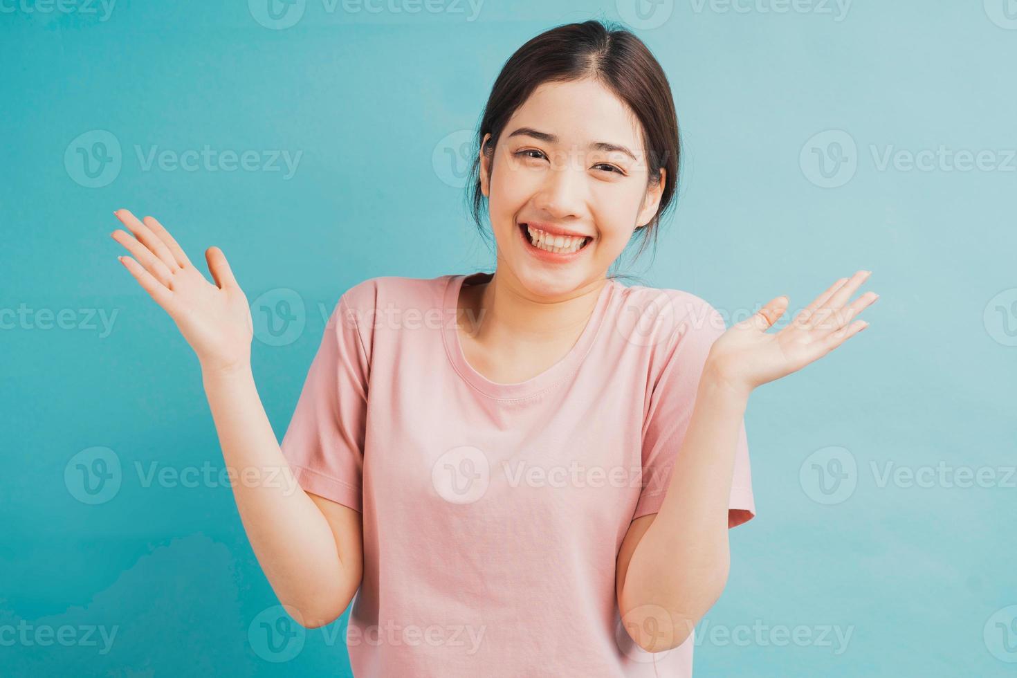 Portrait of cheerful girl raising her hand on green background photo
