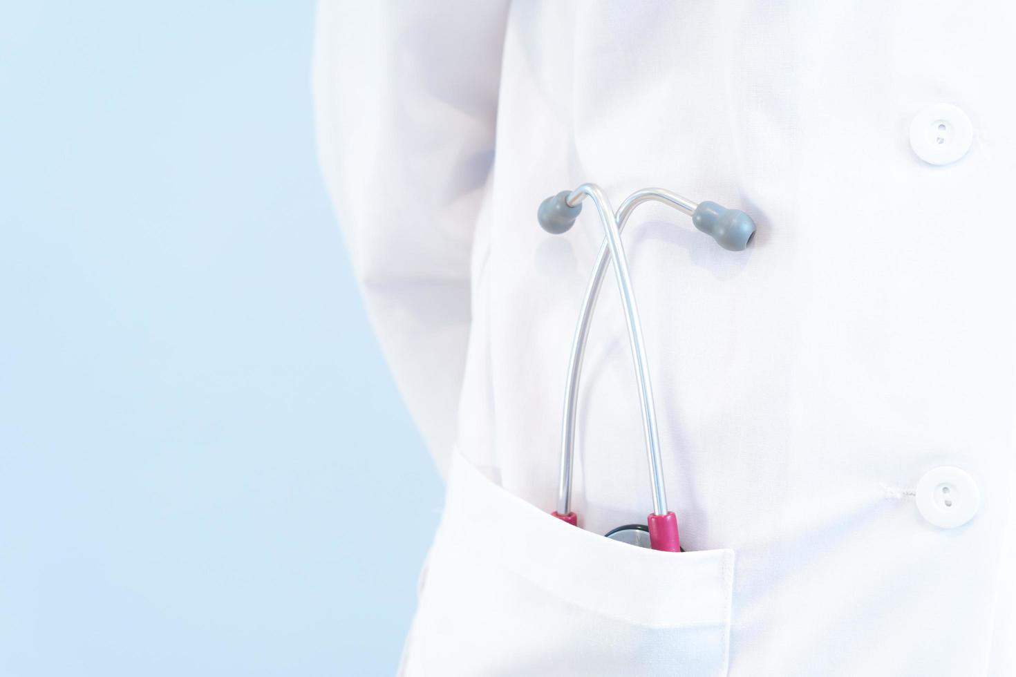 A doctor in whiite gown with stathoscope in the pocket on the blue background photo