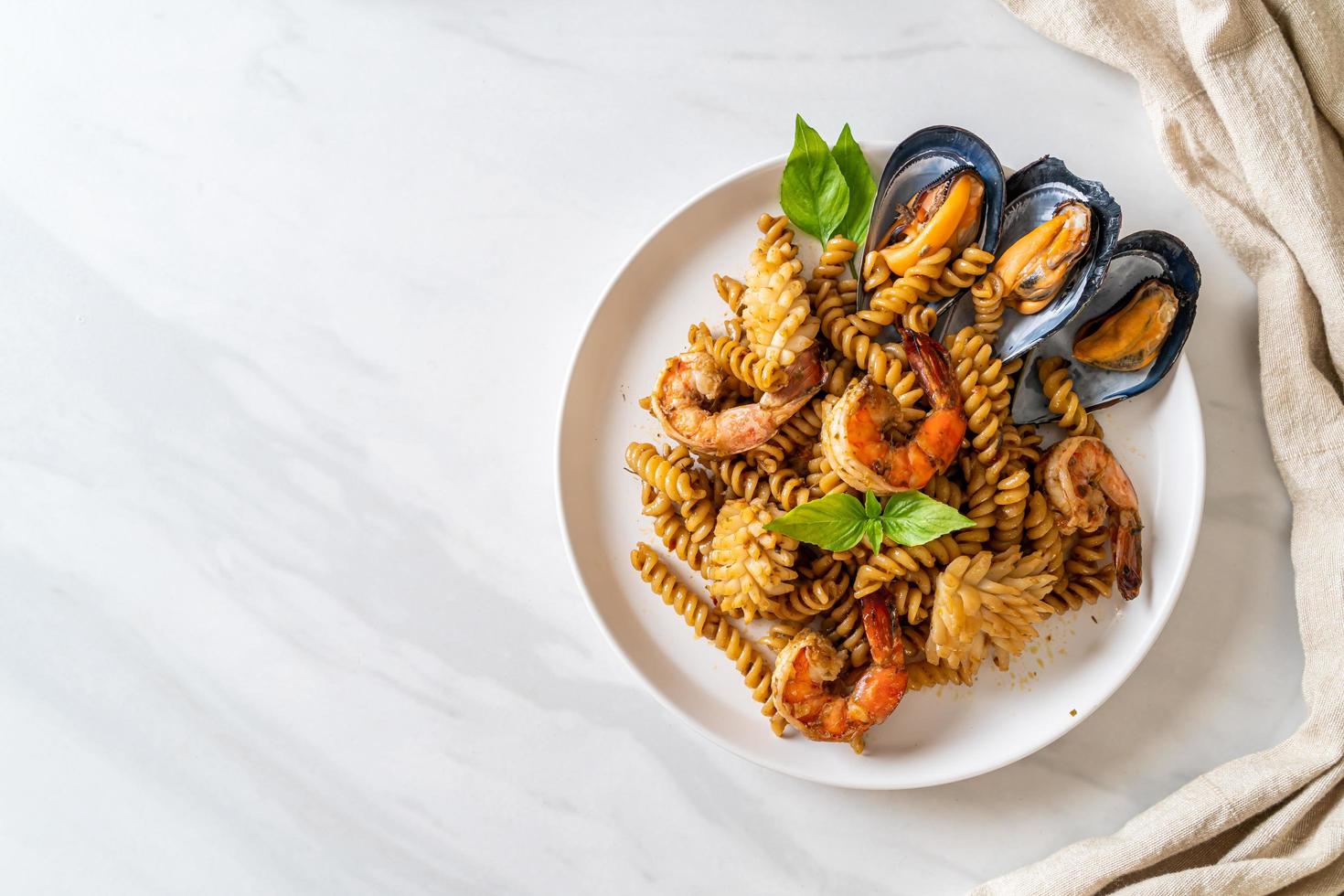 pasta en espiral salteada con salsa de mariscos y albahaca - estilo de comida fusión foto