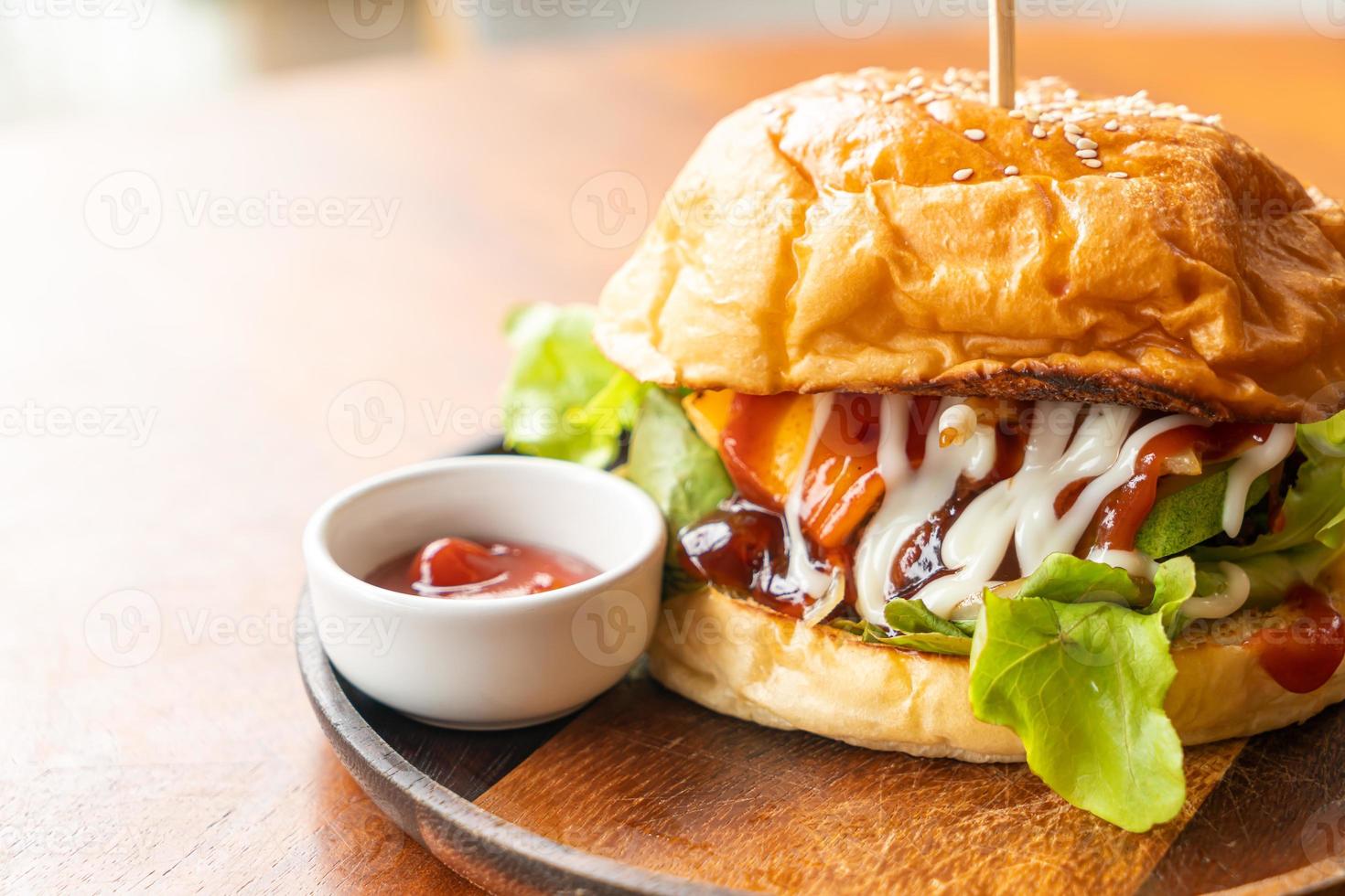 Hamburguesa de ternera con queso y salsa sobre placa de madera foto