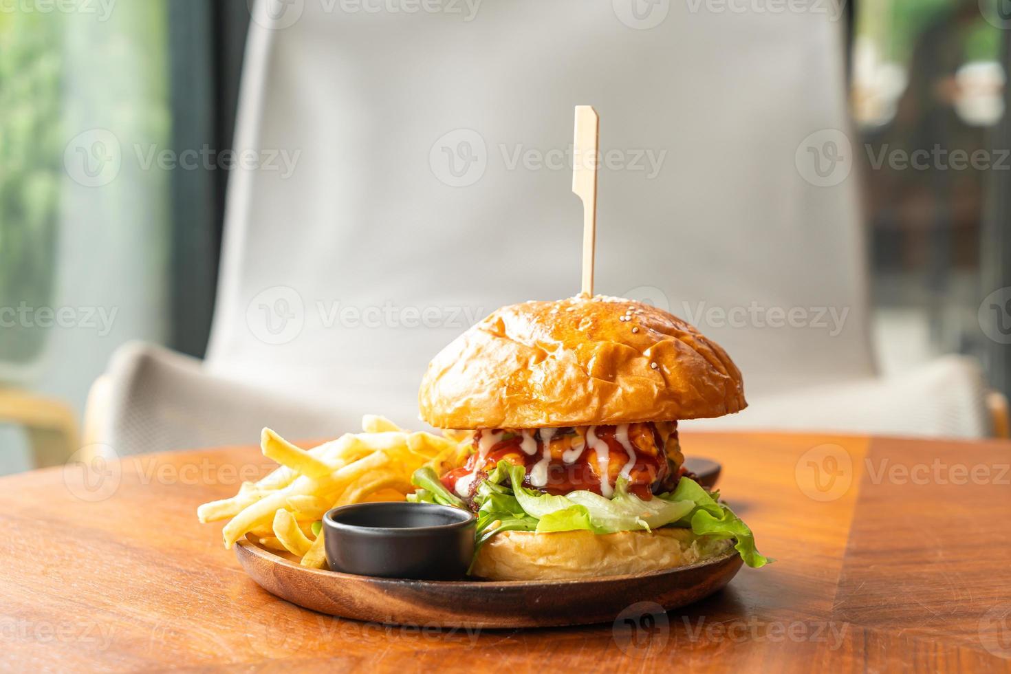 Hamburguesa de ternera con queso y salsa sobre placa de madera foto