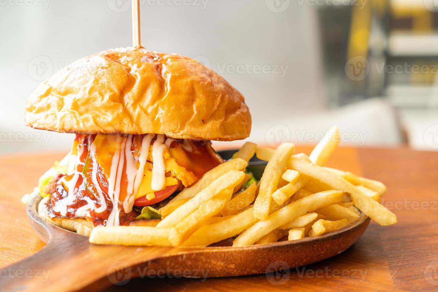 Hamburguesa de ternera con queso y salsa sobre placa de madera foto