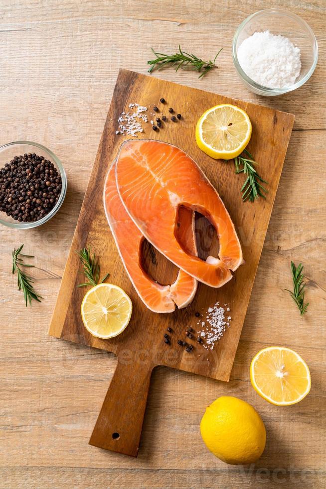 Fresh raw salmon fillet steak with ingredients on board photo