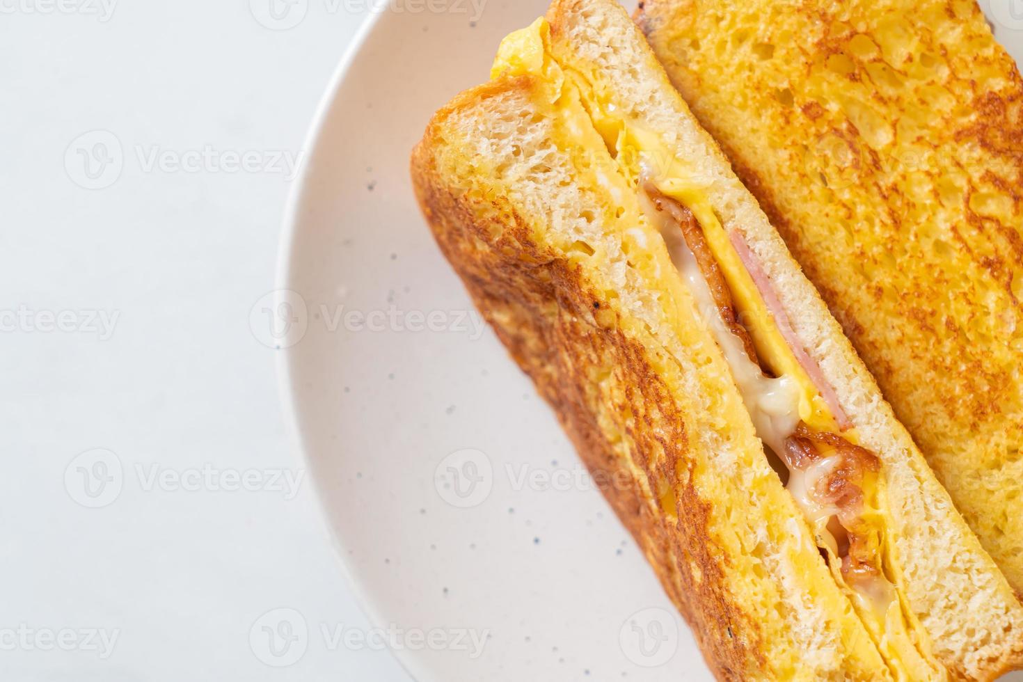 tostada francesa casera con sándwich de jamón, tocino y queso con huevo foto