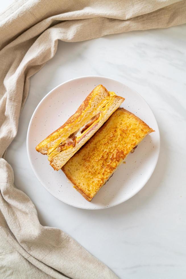 tostada francesa casera con sándwich de jamón, tocino y queso con huevo foto