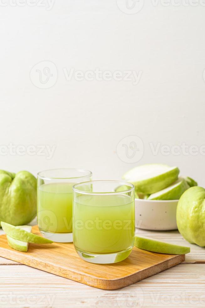 Vaso de jugo de guayaba fresca con fruta fresca de guayaba en la mesa de madera foto