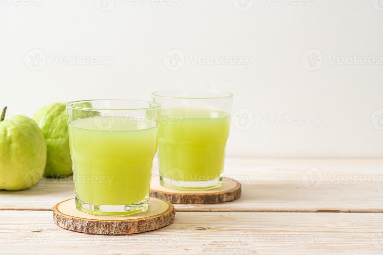 Vaso de jugo de guayaba fresca con fruta fresca de guayaba en la mesa de madera foto