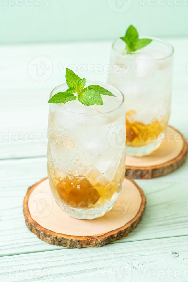 Jugo de ciruela helado con soda y menta en la mesa de madera - bebida refrescante foto