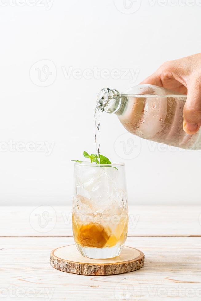 Jugo de ciruela helado con soda y menta en la mesa de madera - bebida refrescante foto