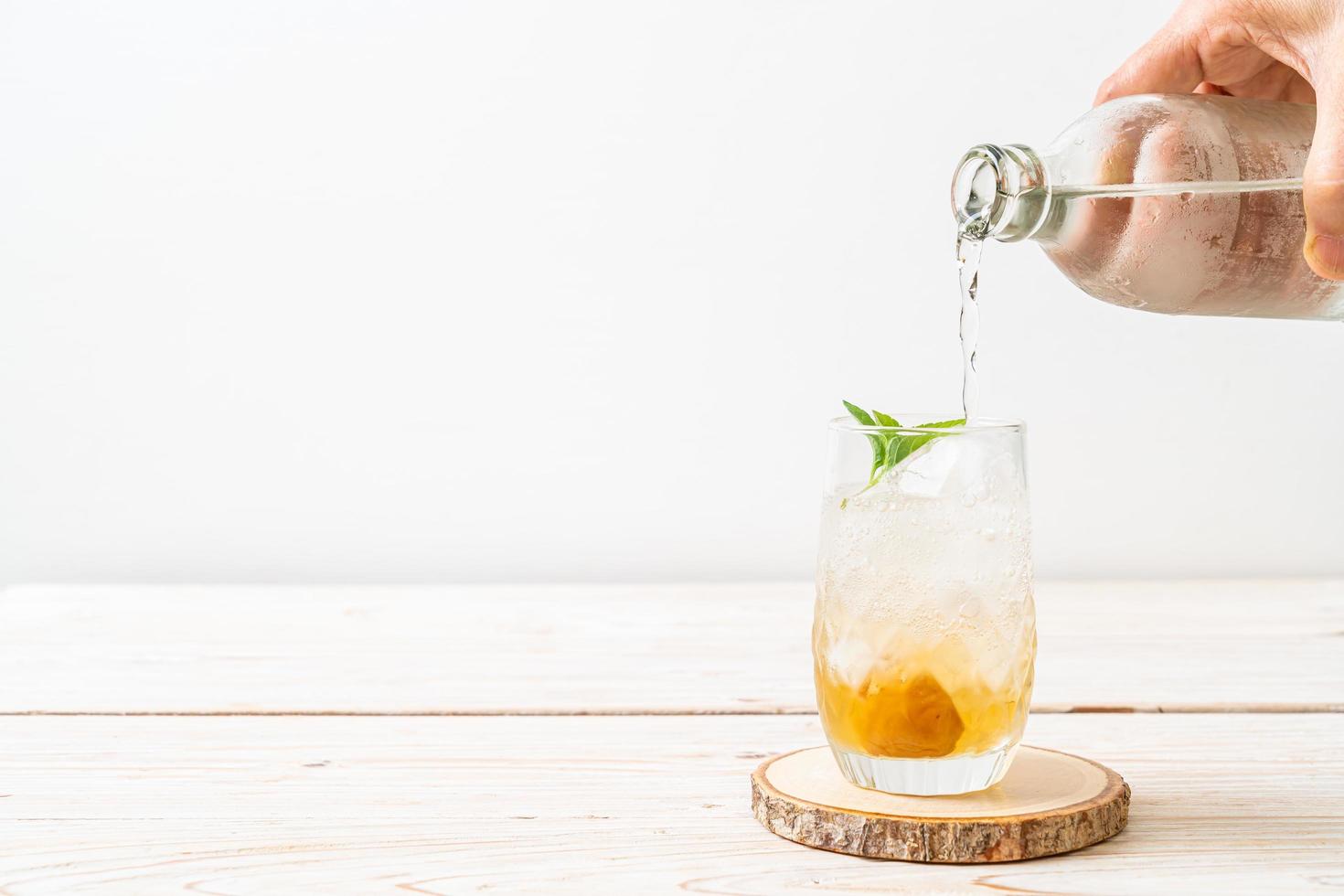 Jugo de ciruela helado con soda y menta en la mesa de madera - bebida refrescante foto