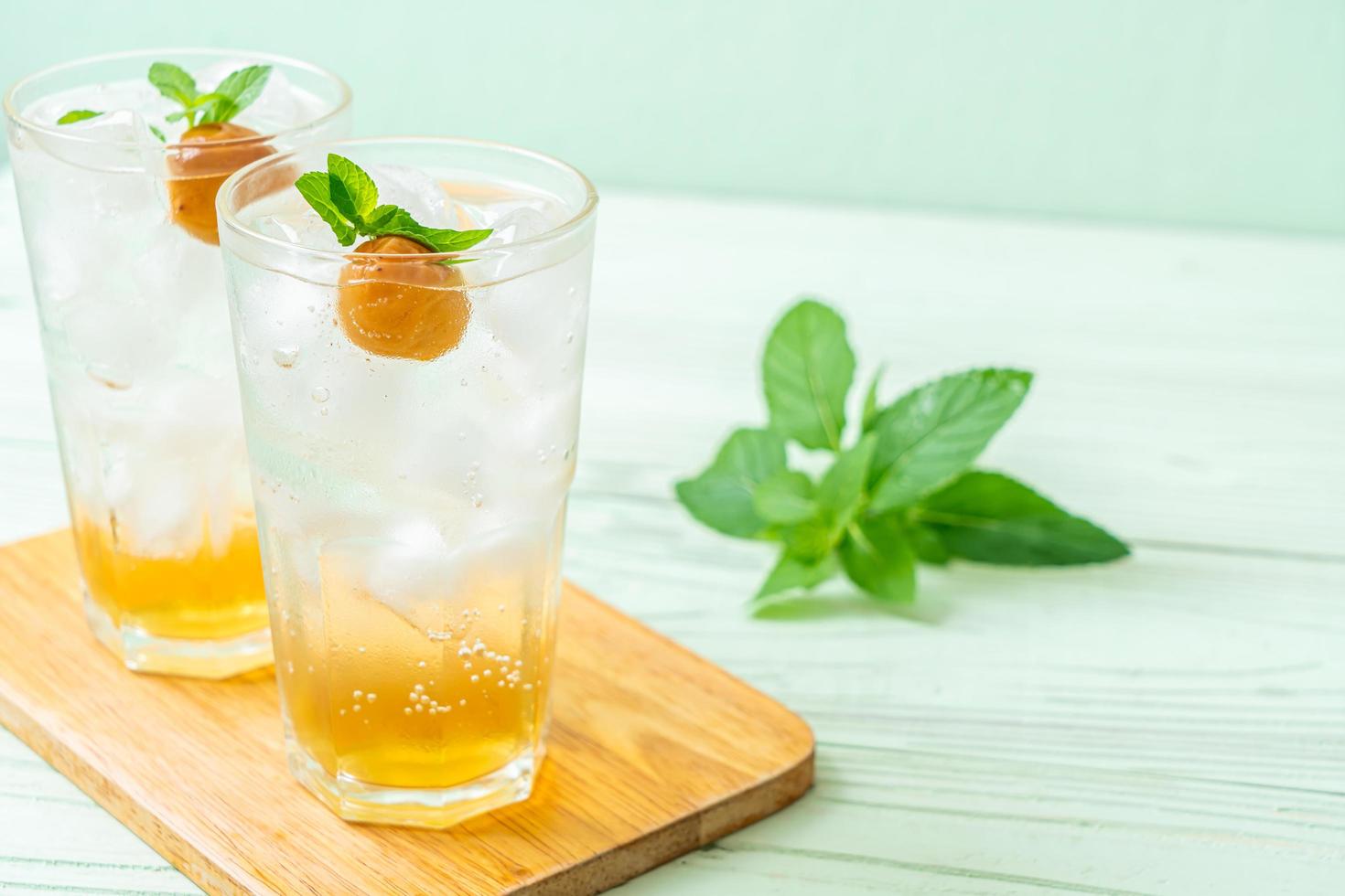 Jugo de ciruela helado con soda y menta en la mesa de madera - bebida refrescante foto