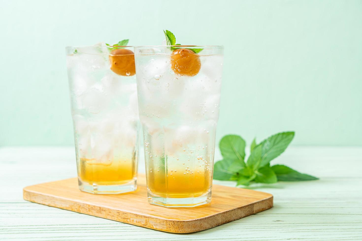 Jugo de ciruela helado con soda y menta en la mesa de madera - bebida refrescante foto