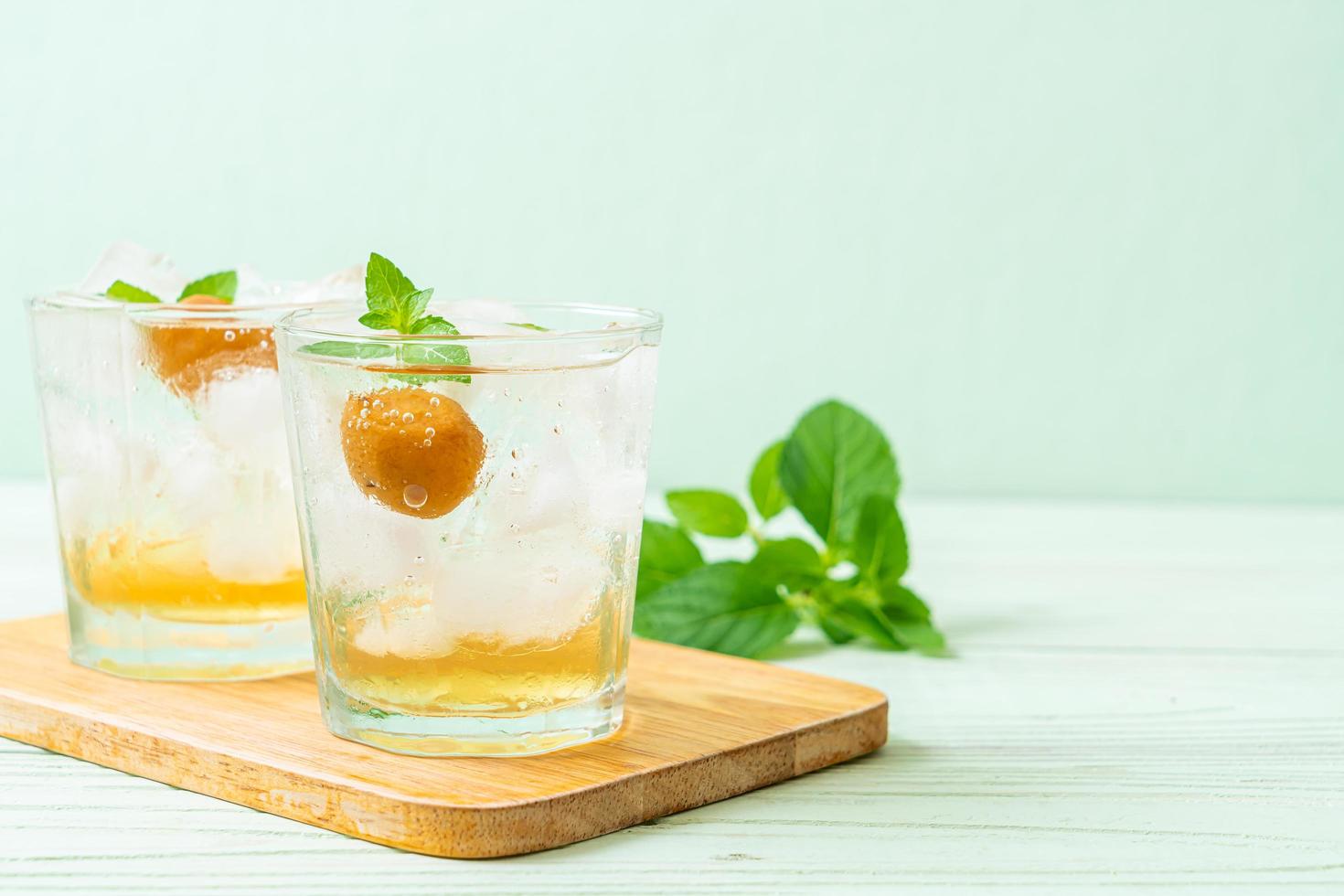 Iced plum juice with soda and peppermint on the wood table - refreshment drink photo