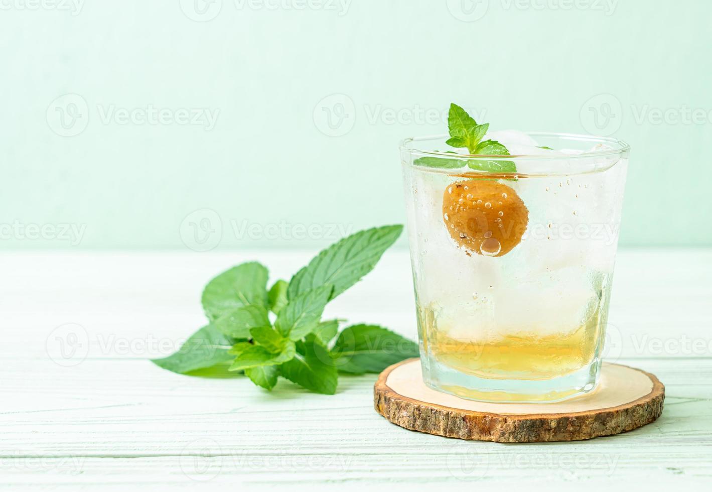 Jugo de ciruela helado con soda y menta en la mesa de madera - bebida refrescante foto