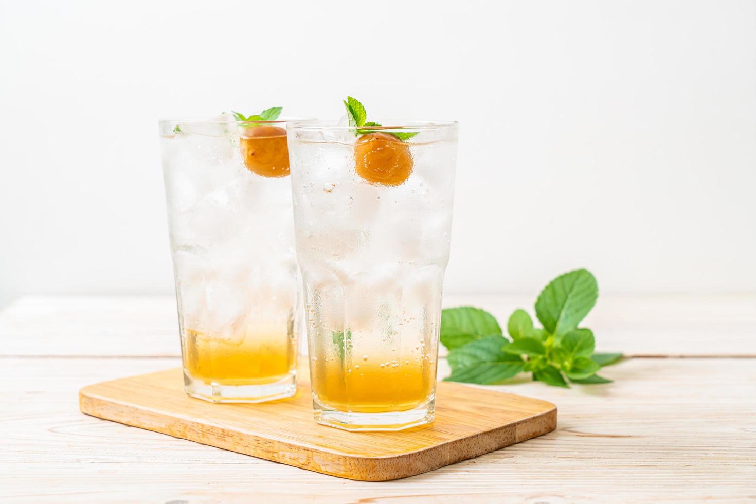 Jugo de ciruela helado con soda y menta en la mesa de madera - bebida refrescante foto