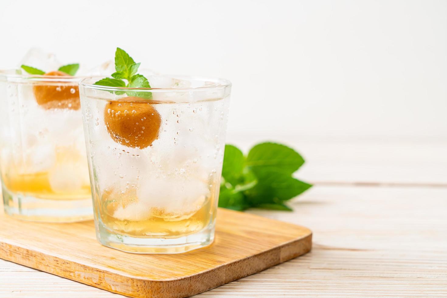 Jugo de ciruela helado con soda y menta en la mesa de madera - bebida refrescante foto