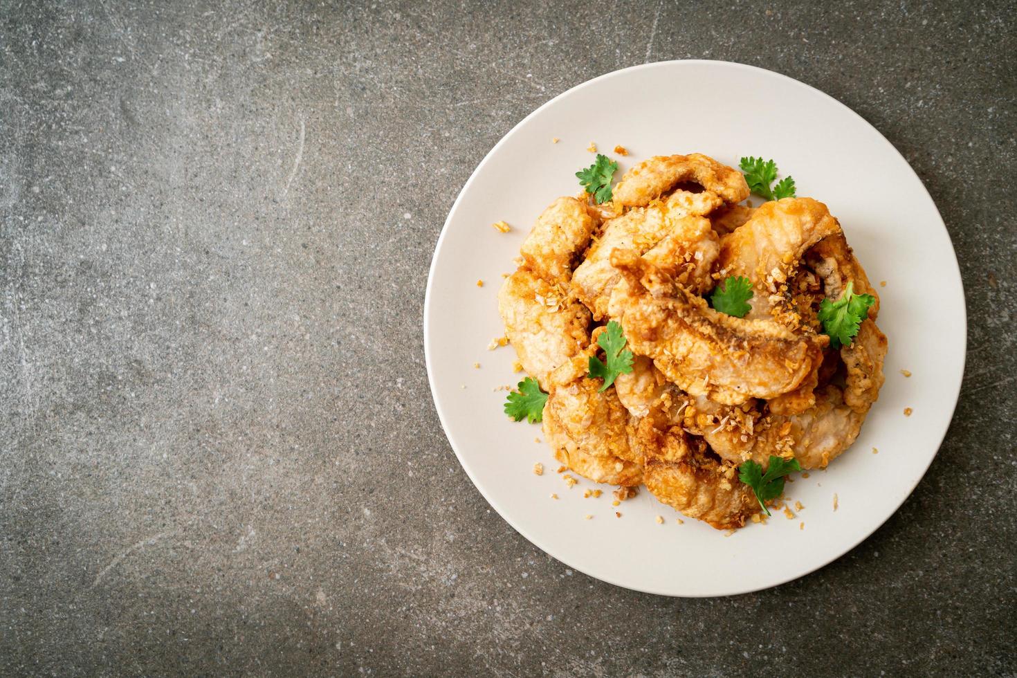 Fried fish with garlic on plate photo