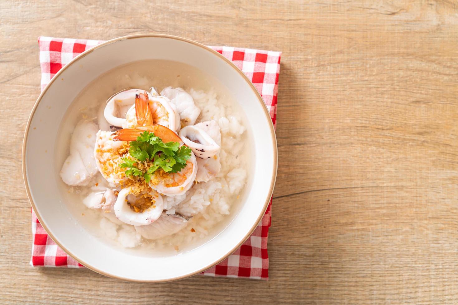 Porridge or boiled rice soup with seafood of shrimp, squid, and fish in a bowl photo