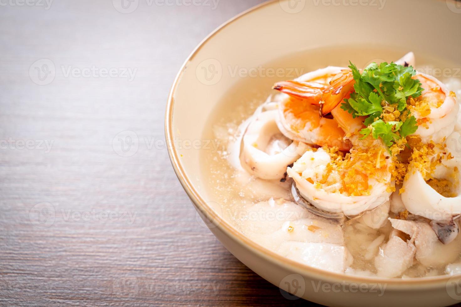 Porridge or boiled rice soup with seafood of shrimp, squid, and fish in a bowl photo