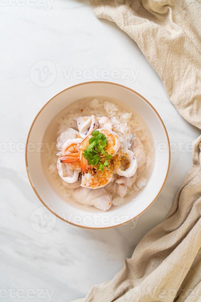 Porridge or boiled rice soup with seafood of shrimp, squid, and fish in a bowl photo