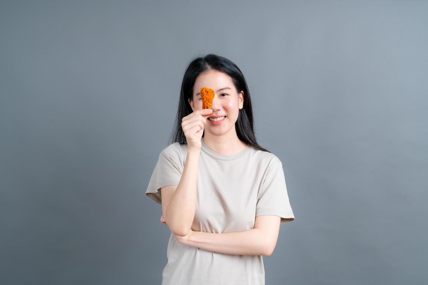 Joven mujer asiática con cara feliz y disfruta comiendo pollo frito foto