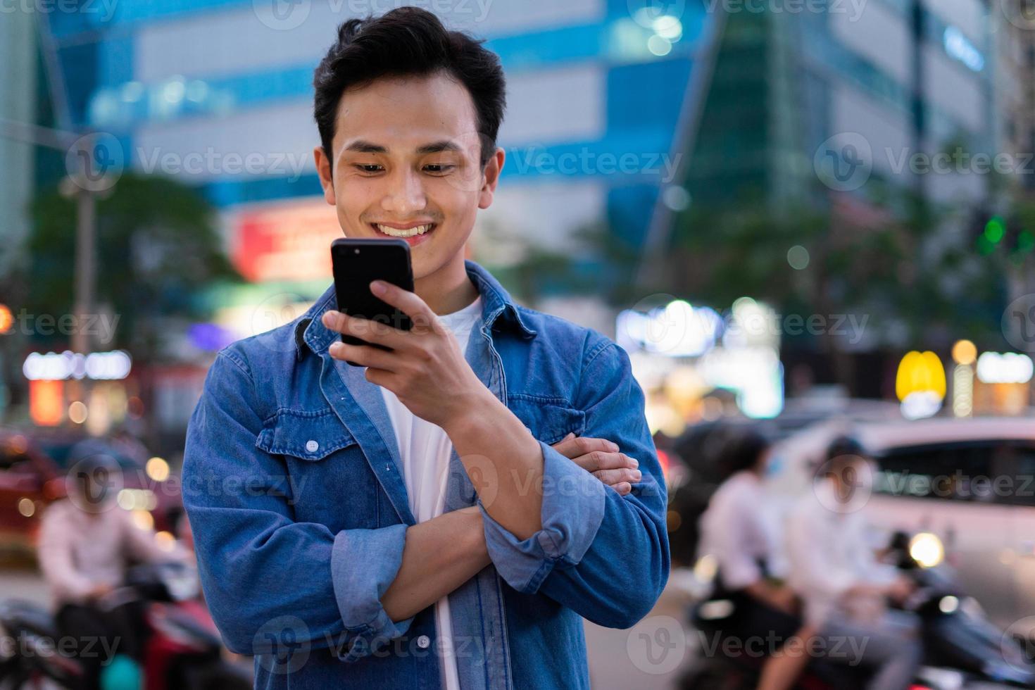 Young Asian man using smartphone on the street at night photo