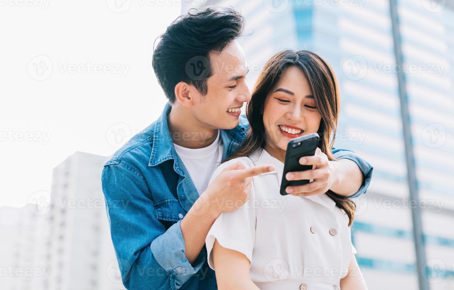 Young Asian couple using smartphone together on the street photo