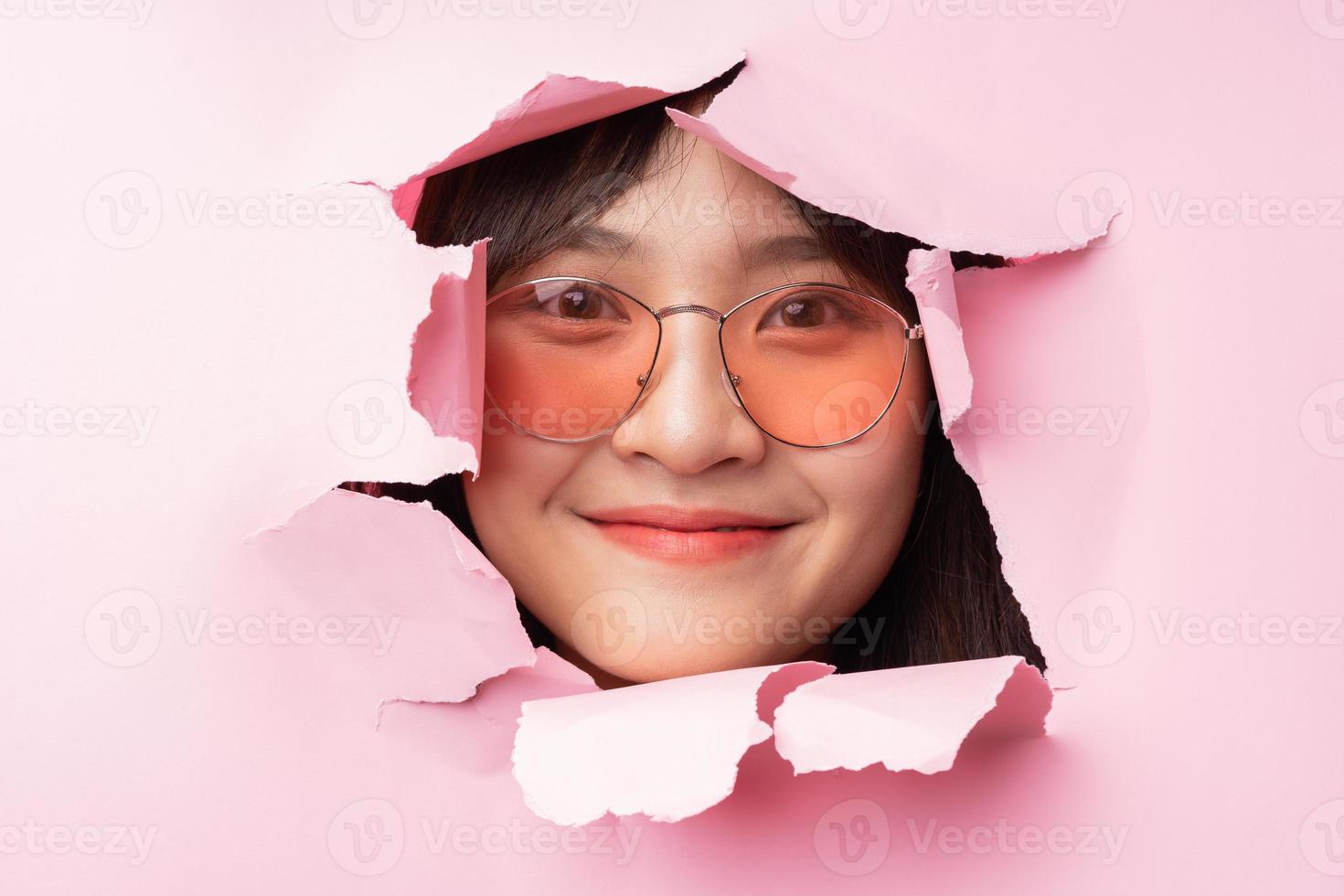 Young Asian woman poked her head through the torn paper photo