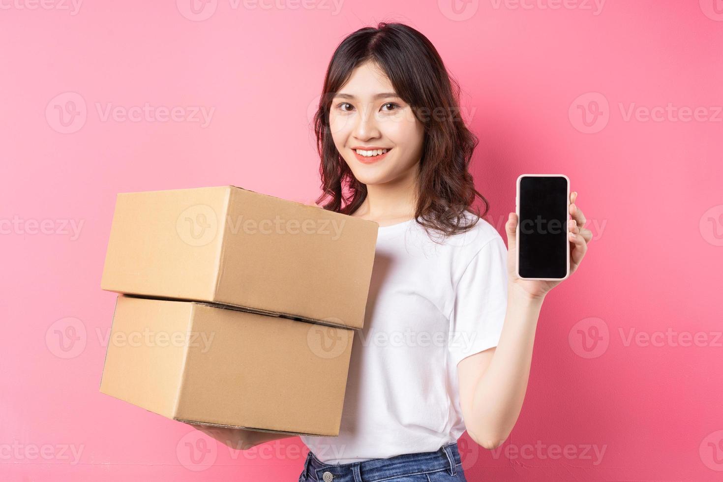 Mujer sosteniendo teléfono y caja de carga riendo alegremente sobre fondo foto