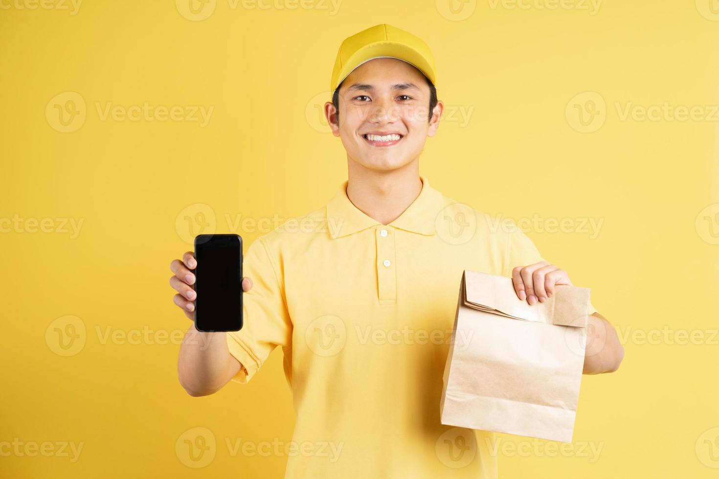 Portrait of male deliveryman holding shopping bag and phone photo